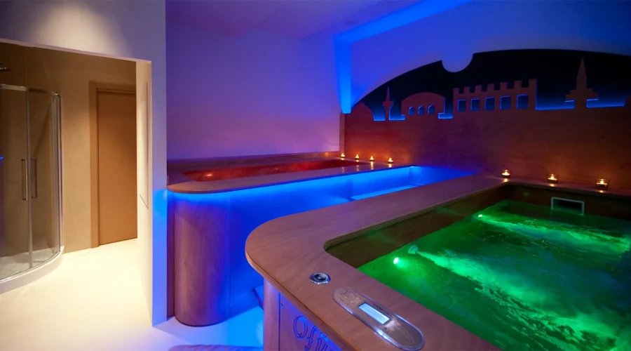 Vasca idromassaggio in una spa con illuminazione colorata e ambiente rilassante.